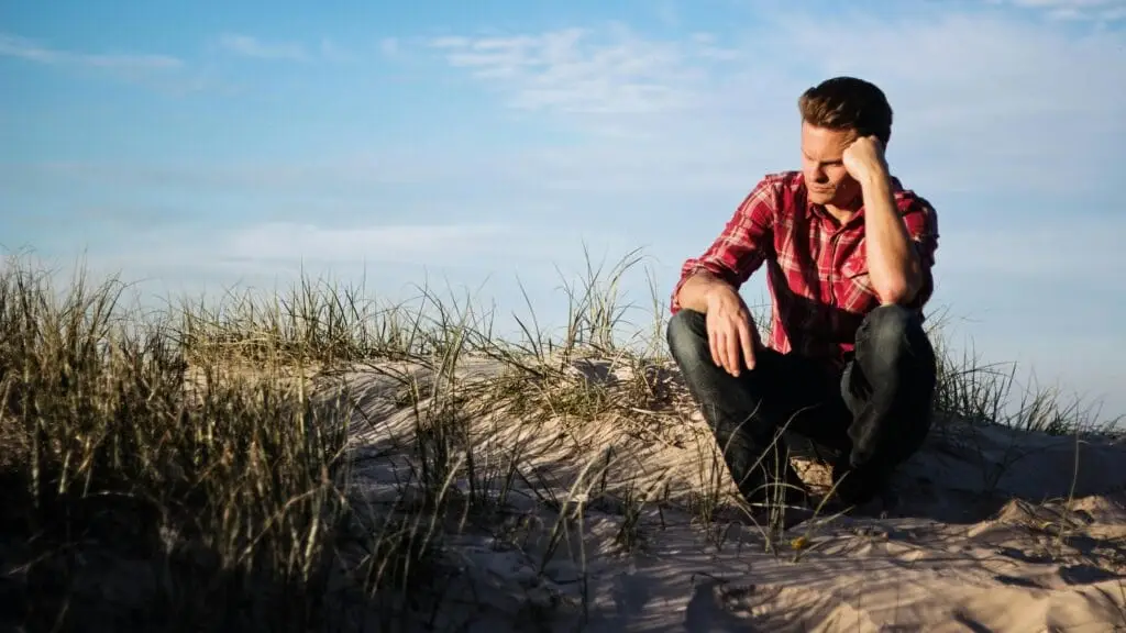 A guy sitting on the grass, pondering about life.